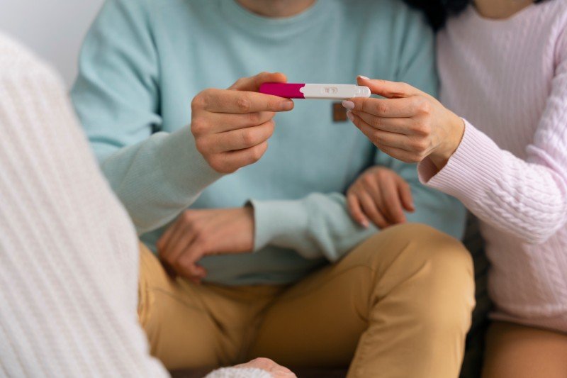 Couple holding a positive pregnancy test while beginning their fertility and pregnancy journey.
