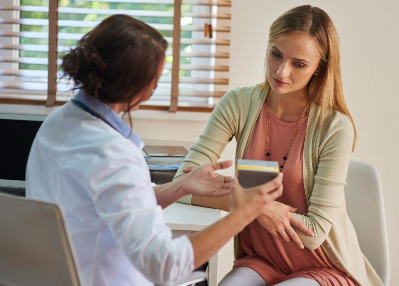 Gynecologist consulting a woman about menstrual health and discussing treatment options during a clinic visit.