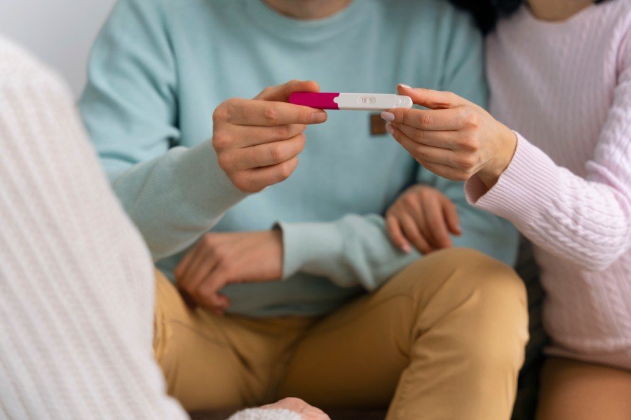 Woman holding a positive pregnancy test during a confidential consultation about pregnancy options.