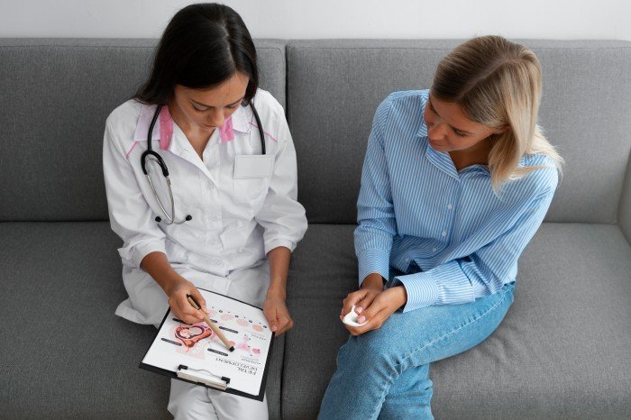 Doctor discussing menstrual disorder treatment with a female patient using a medical diagram.