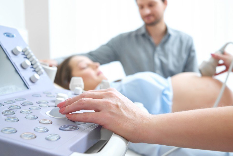 Gynecologist performing an ultrasound examination on a pregnant woman while her partner looks on